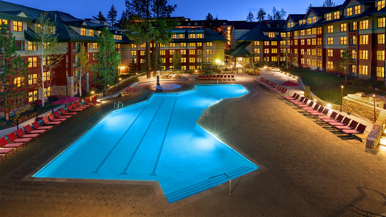 Illuminated outdoor pool and exterior of Marriott's Timber Lodge resort timeshare at dusk